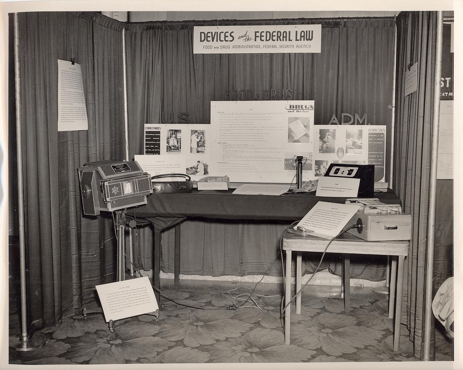 Figure 4 — The regulator's own display: "DEVICES and FEDERAL LAW," a Food and Drug Administration exhibit of fraudulent medical devices, the machines laid out on a draped table with their case documents pinne…