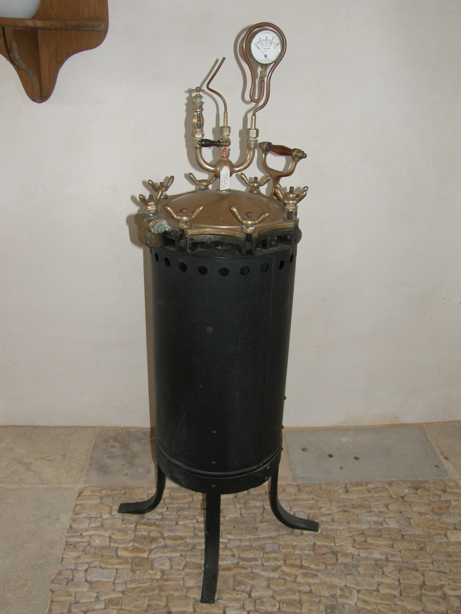 Figure 3 — A Chamberland autoclave — the machine described above, and the direct ancestor of every sterilizer in the modern operating suite. The cylindrical vessel stands on its own legs; the pressure gauge a…